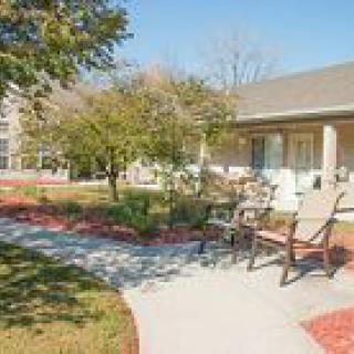 A serene garden setting with a pathway, benches, and surrounding trees near a building.
