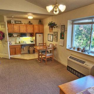 A cozy residential interior featuring a small kitchen and dining area with a large window.