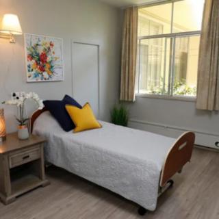 A minimalist bedroom with a single bed, nightstand, and large window.