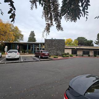 A view of a modern building with an adjoining parking lot, surrounded by autumn foliage.