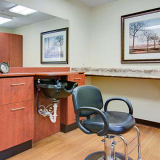 A hair salon station with a chair and sink, featuring framed artwork on the walls.
