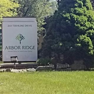 A welcoming sign for Arbor Ridge surrounded by lush greenery.