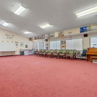 An empty classroom with a row of chairs, a piano, and colorful decorations on the walls.