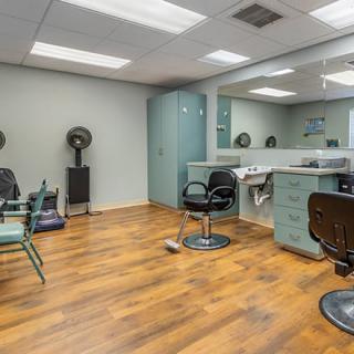 Modern hair salon with styling chairs and mirrors on a hardwood floor.