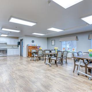 A bright and modern dining area with tables and chairs, adjacent to a kitchen.