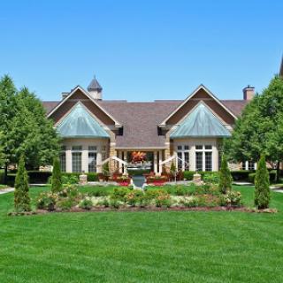 A beautiful home surrounded by well-manicured lawns and vibrant landscaping under a clear blue sky.