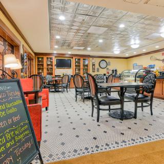 A cozy cafe interior with neatly arranged tables and chairs, featuring a prominent menu board.