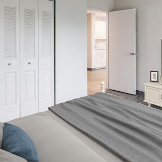 A minimalist bedroom featuring a neatly made bed, closet doors, and simple decor.