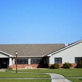 A suburban residential building with a well-maintained lawn and clear blue sky.