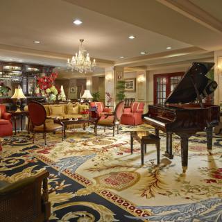 A luxurious hotel lobby featuring a grand piano, elegant seating, and a beautiful chandelier.