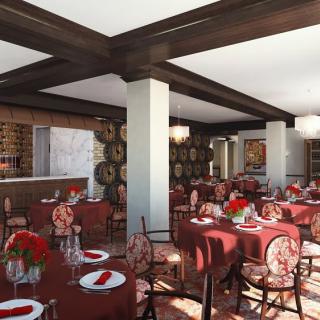 A cozy restaurant interior featuring tables set with red tablecloths and elegant decor.