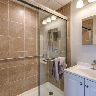Modern bathroom with a glass-door shower, tiled walls, and a sleek sink area.
