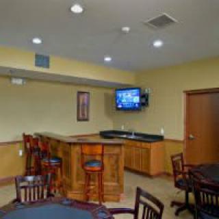 A cozy indoor bar area with a television, wooden furniture, and seating arrangements.