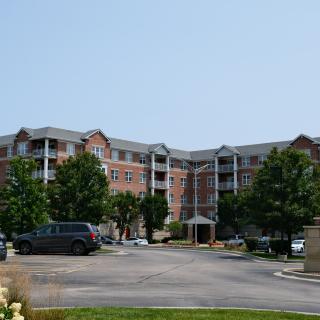 A residential apartment building with cars parked in the front parking lot.