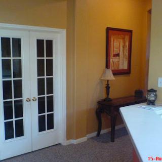 A cozy interior space featuring French doors, a small table with a lamp, and warm wall colors.