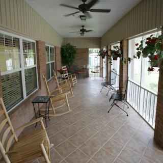 A cozy porch with rocking chairs and ceiling fans, perfect for relaxing outdoors.
