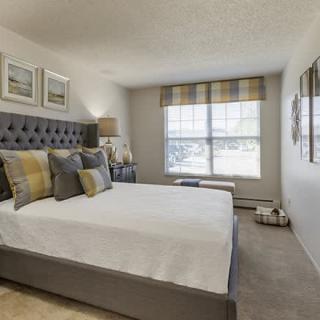 A modern bedroom with a neatly made bed, pillows, and tasteful decor.