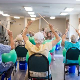 A group of seniors participating in a fitness class using exercise balls and chairs.