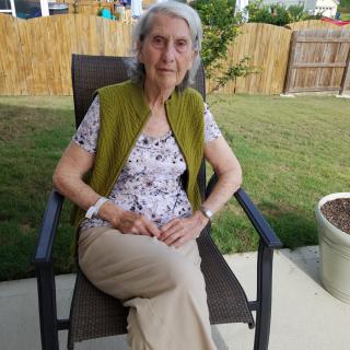 A woman sitting outside in a garden, relaxing on a chair.