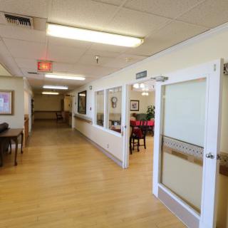 A well-lit hallway with wooden flooring and multiple doors leading to different rooms.