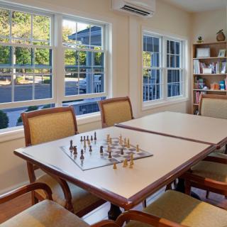 A cozy game room with a chess set on the table and large windows allowing natural light to fill the space.