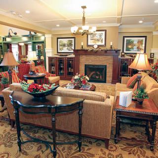 A cozy living room with elegant furniture and a central fireplace, featuring warm lighting and tasteful decor.