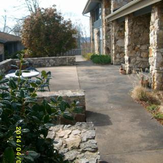 An outdoor patio area with stone walls and furniture alongside a building.