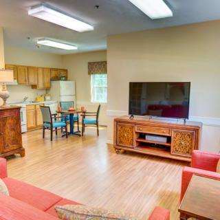 A cozy living space with an open kitchen, featuring a comfortable sofa, television, and dining area.