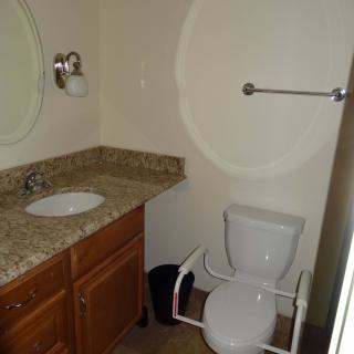 A compact bathroom with a sink, toilet, and wall-mounted mirror.