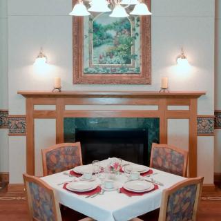 An elegantly set table in a cozy dining room featuring a fireplace, artwork, and ambient lighting.