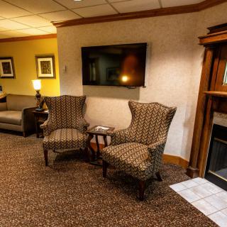 A cozy living room with chairs, a television, and a fireplace.