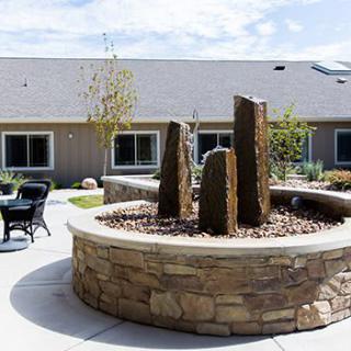 A stone fountain in a tranquil garden setting with patio seating.
