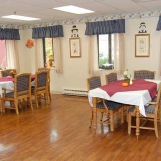 A cozy dining room with several tables and chairs on a wooden floor, adorned with curtains and decor.