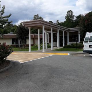 A view of a building entrance with a parking area under a partly cloudy sky.