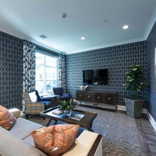 A modern living room with stylish wallpaper, a comfortable sofa, and a television mounted on the wall.