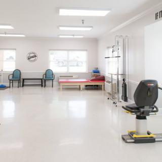 A bright and spacious physical therapy room equipped with various rehabilitation tools.