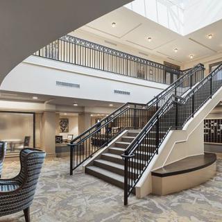 A modern lobby interior featuring a central staircase and elegant seating area.