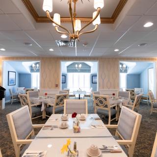 A well-lit, elegant dining room with neatly arranged tables and chairs.