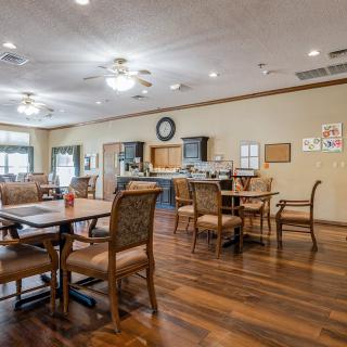 A spacious dining area with wooden furniture and a kitchen in the background.