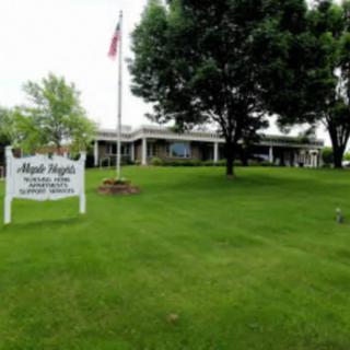 A building with a well-maintained lawn, trees, and an American flag near a sign.