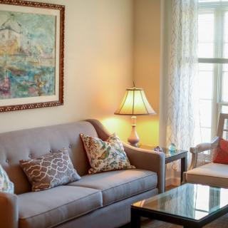 A cozy living room featuring a comfortable sofa with decorative pillows, a lamp, and a painting on the wall.