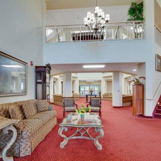 A spacious and elegant lobby area featuring comfortable seating, a chandelier, and red carpeting.