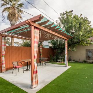 A cozy backyard featuring a pergola with outdoor seating and a well-maintained lawn.