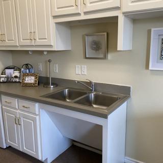 A kitchen area with a double sink, white cabinets, and countertop appliances.