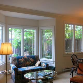 A cozy living room with ample natural light streaming through large windows, featuring a comfortable sofa and elegant decor.