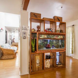 A cozy living room featuring a wooden shelf with an aquarium and various decorative items.