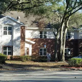 Suburban house with brick facade and trees in the front yard.