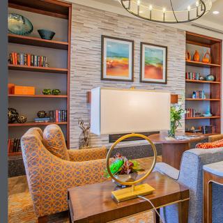 A modern living room with colorful decor, featuring artwork on the walls and neatly arranged shelves.