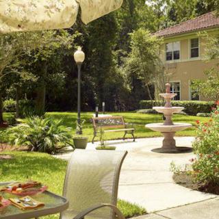 A serene garden patio with a fountain, surrounded by lush greenery.