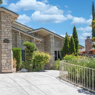 A brick house with a driveway and well-maintained landscaping under a partly cloudy sky.